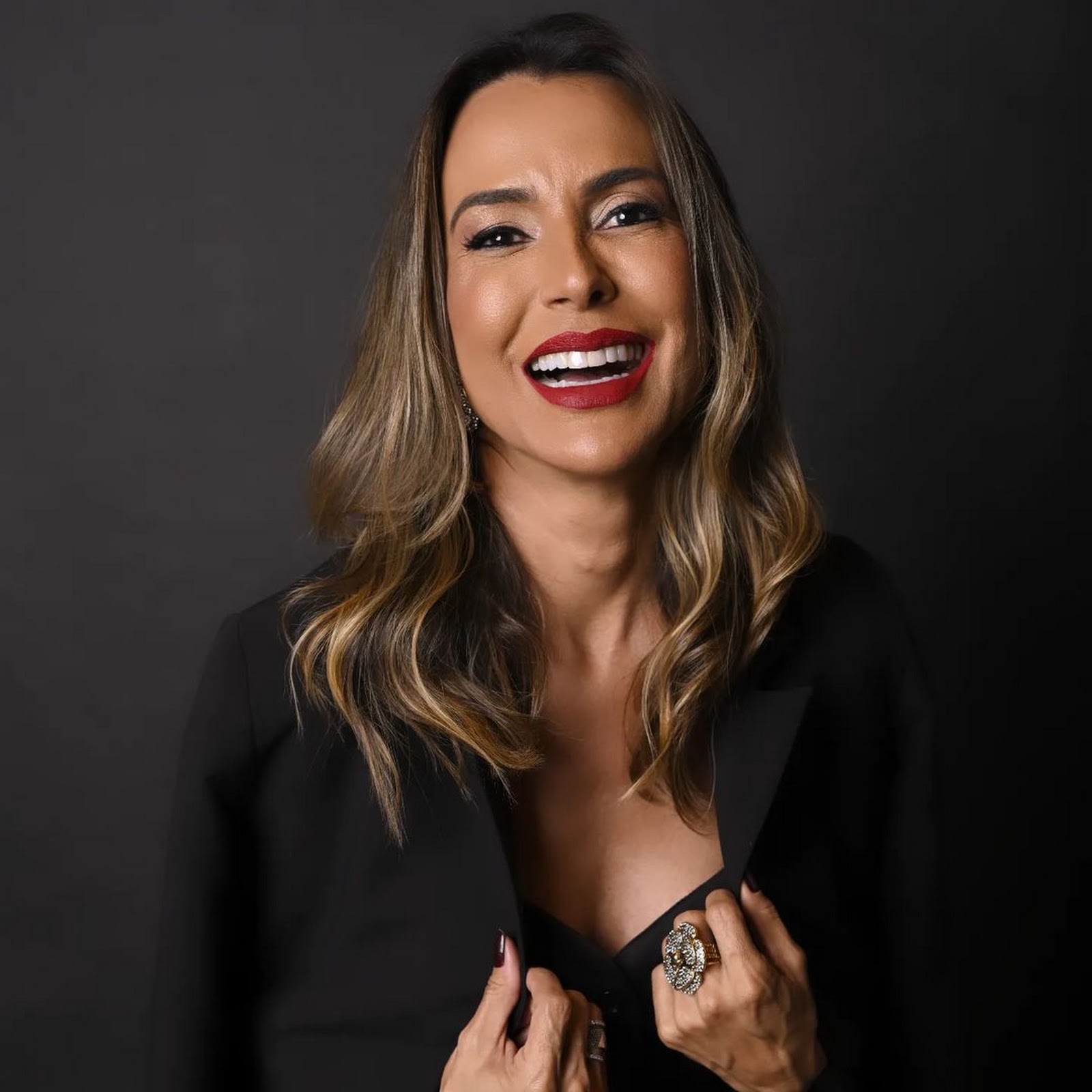Dra. Vanessa Borges em retrato de estúdio sobre fundo preto, sorrindo, com blazer preto